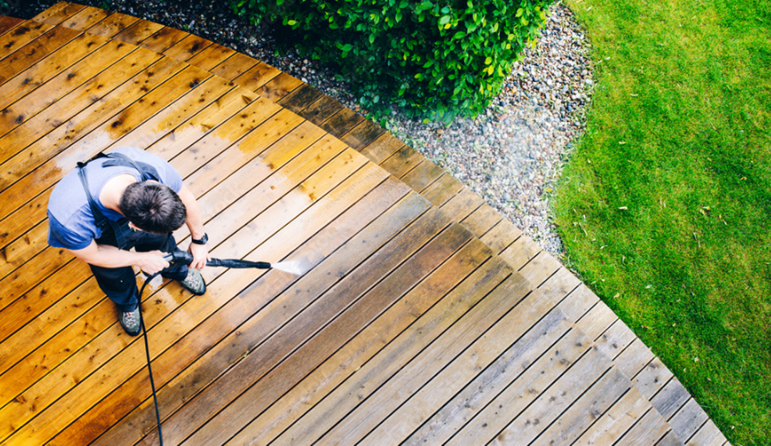 Man using pressure washing to clean wood floor